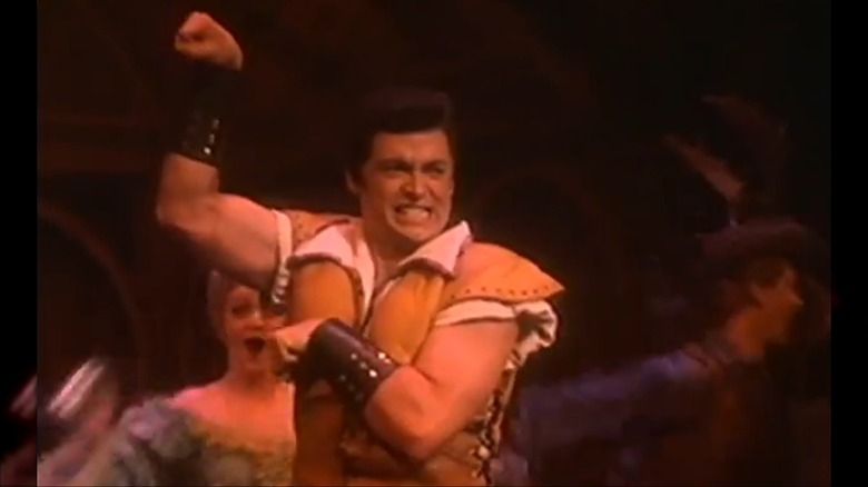 Hugh Jackman flexing his bicep in Gaston costume