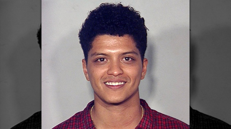 Bruno Mars smiling in his mugshot