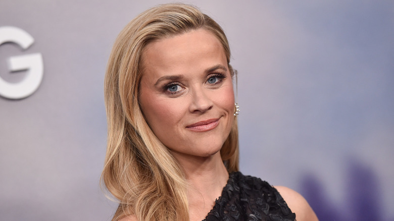 Reese Witherspoon smiling in an off-shoulder black dress