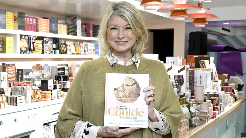 Martha Stewart smiling while holding one of her cookbooks