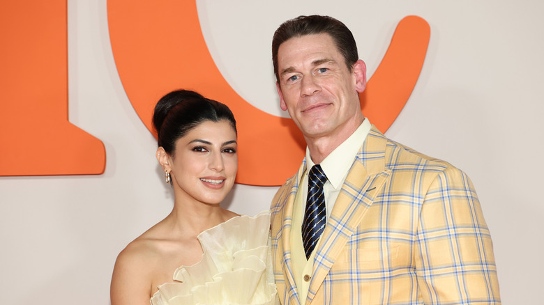 John Cena in a checkered yellow suit beside Shay Shariatzadeh
