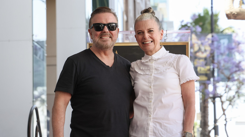 Ricky Gervais wearing black beside Jane Fallon wearing white