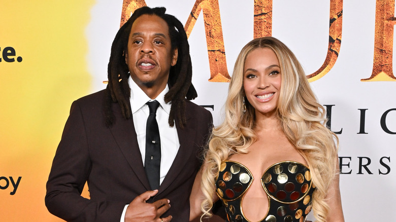 Jay-Z in brown suit and white shirt with Beyonce in black and gold dotted strapless gown