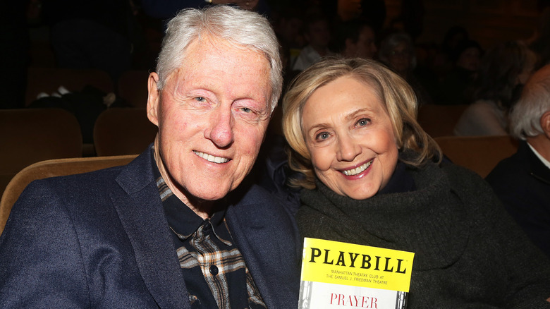 Bill Clinton in blue blazer with Hillary Clinton holding a playbill