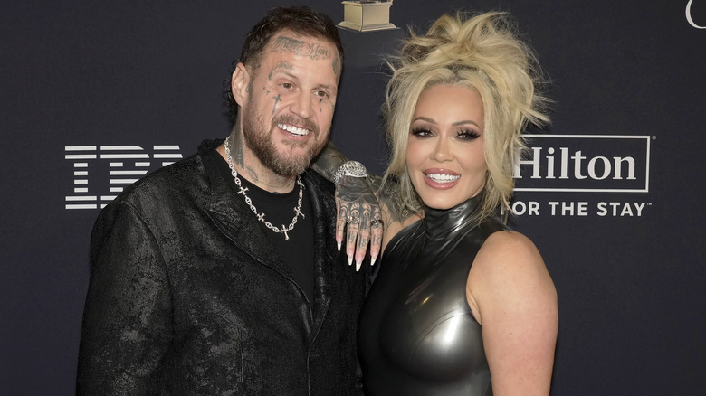 Jelly Roll in black jacket and silver chain with Bunnie Xo in black shiny dress