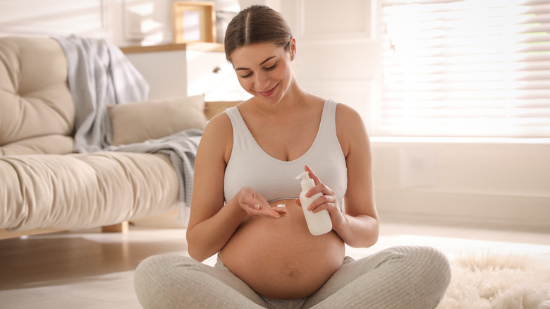 A pregnant woman using body lotion