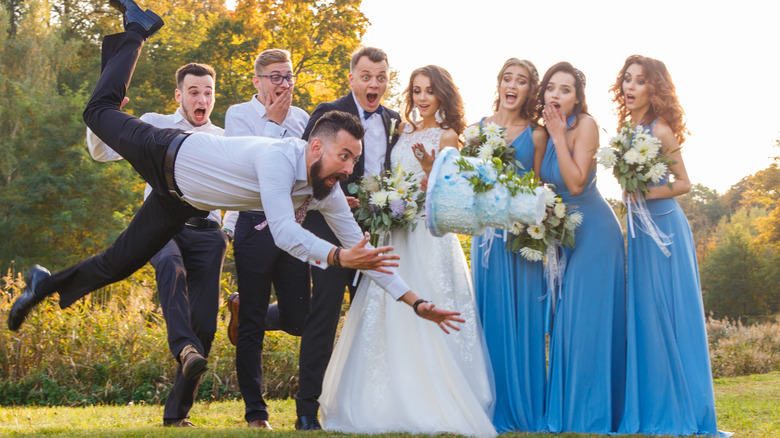 groomsman tripping with wedding cake in front of wedding party