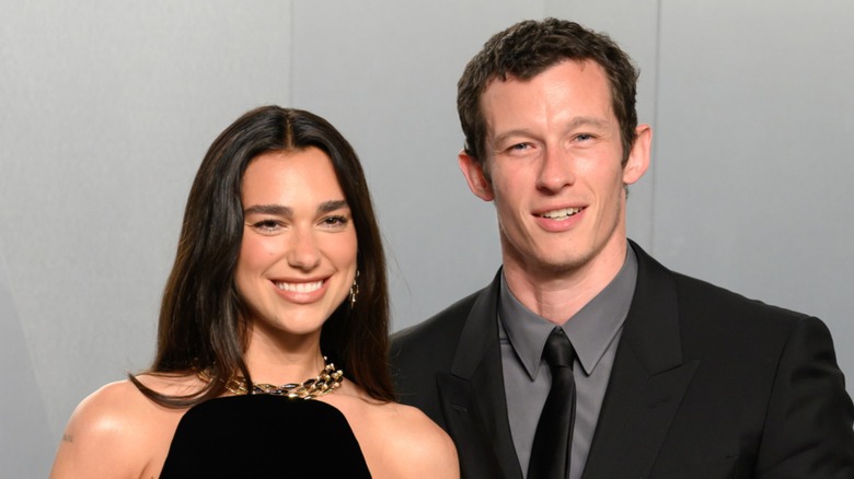 Dua Lipa and Callum Turner smiling on the red carpet in 2026