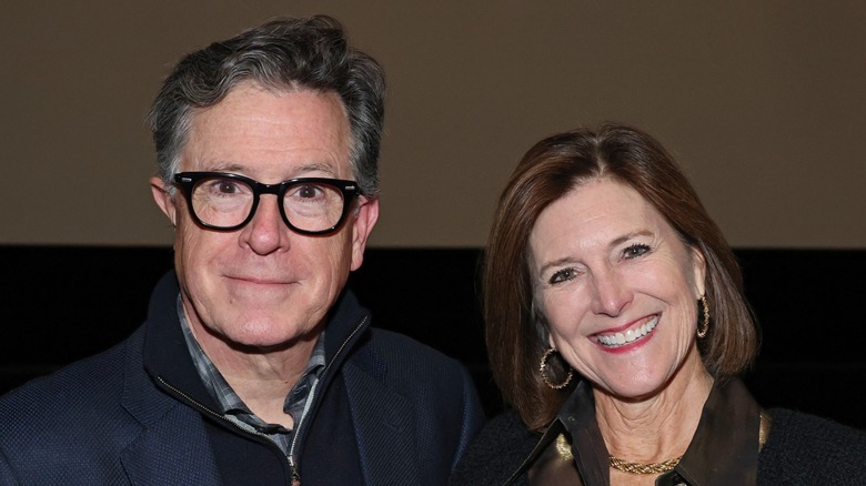 A close-up of Stephen Colbert and Evie McGee Colbert both smiling in front of a movie screen.
