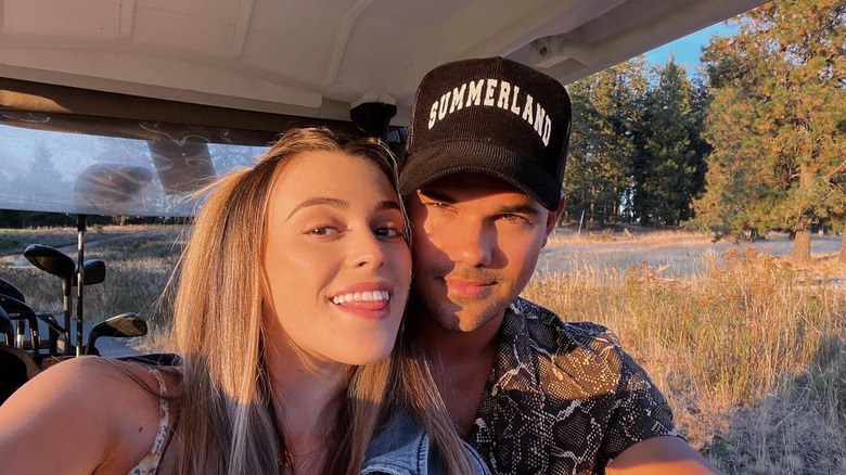 Tay and Taylor Lautner smiling for a selfie in a golf cart.