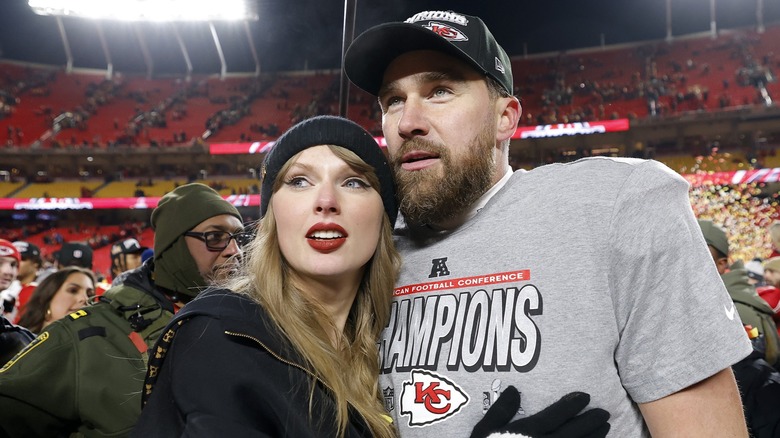 Taylor Swift and Travis Kelce embracing on a stadium field in 2025