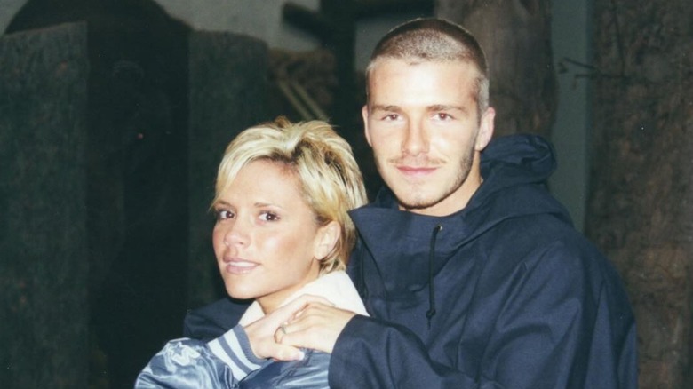 Victoria and David Beckham holding hands and smiling, circa 2000.
