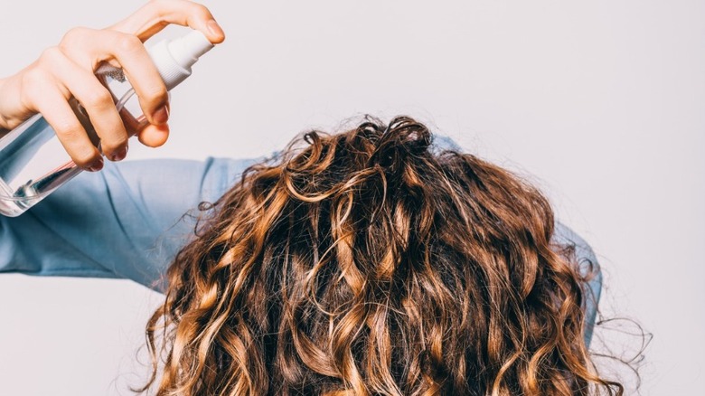 Woman with curly hair applying product to her curls