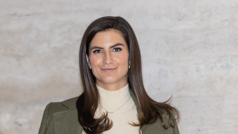 Kaitlan Collins posing in front of a grey stone background