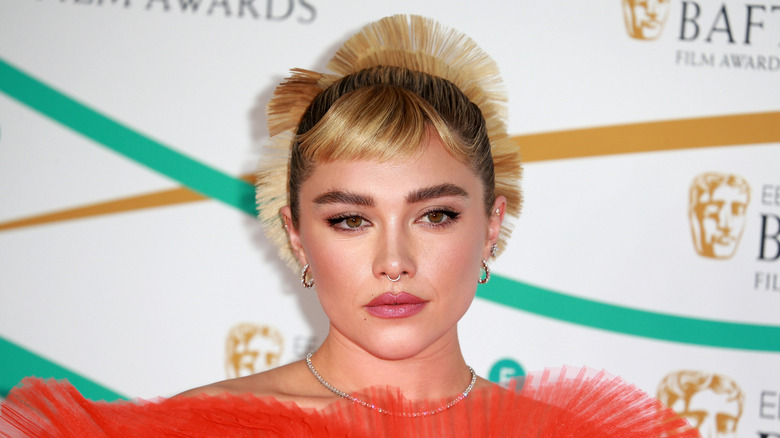 Florence Pugh wearing a micro fringe and orange dress at the BAFTAs