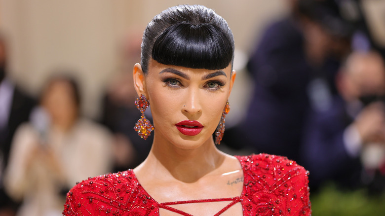 Closeup of Megan Fox in a red dress wearing dramatic micro fringe