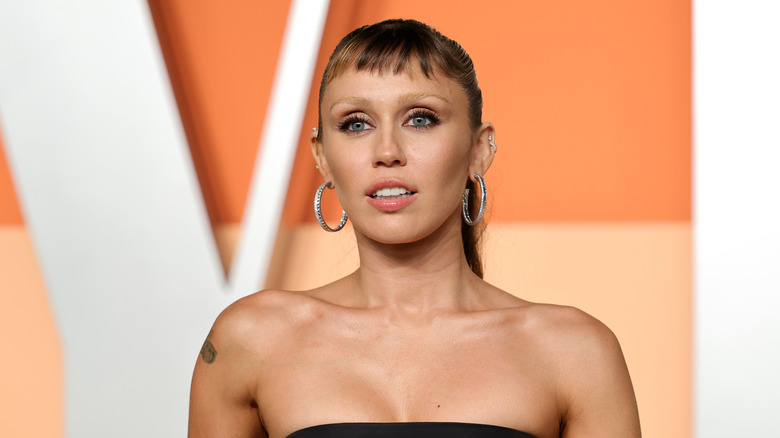 Closeup of Miley Cyrus posing with bleached eyebrows and micro bangs