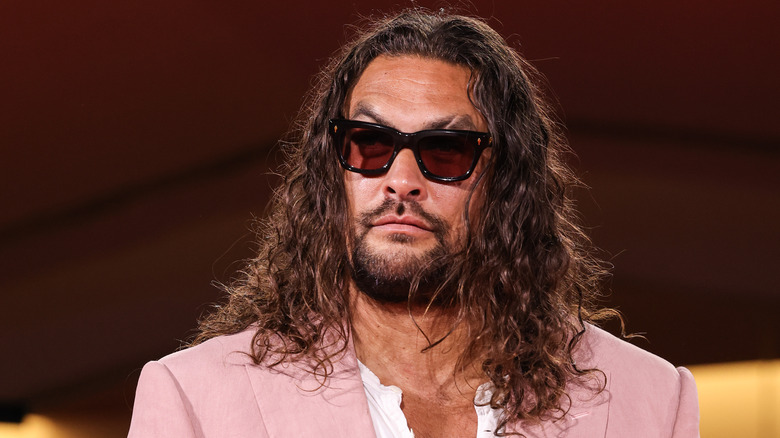 Jasom Momoa wearing pink suit and sunglasses with beard