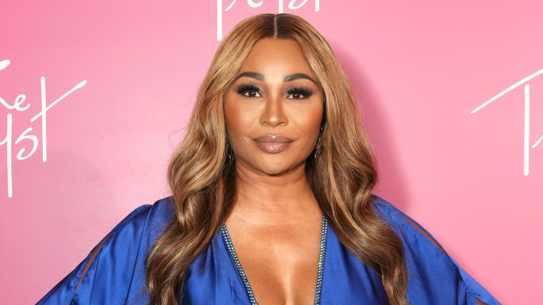 Cynthia Bailey posing in a low-cut blue dress