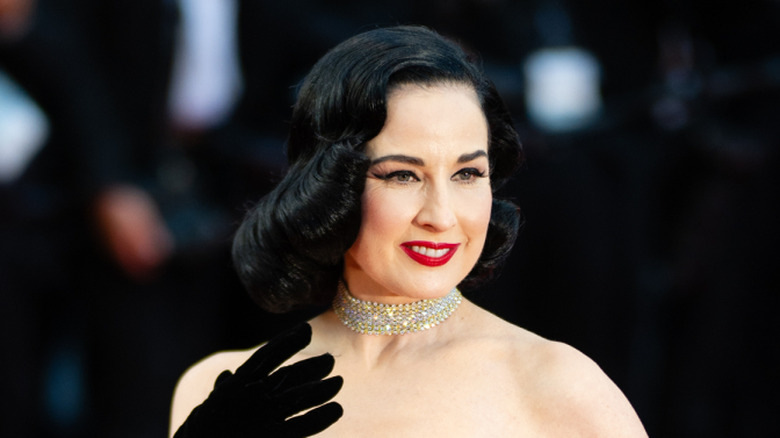 Dita Von Teese on the red carpet in a pink gown and black sleeve gloves