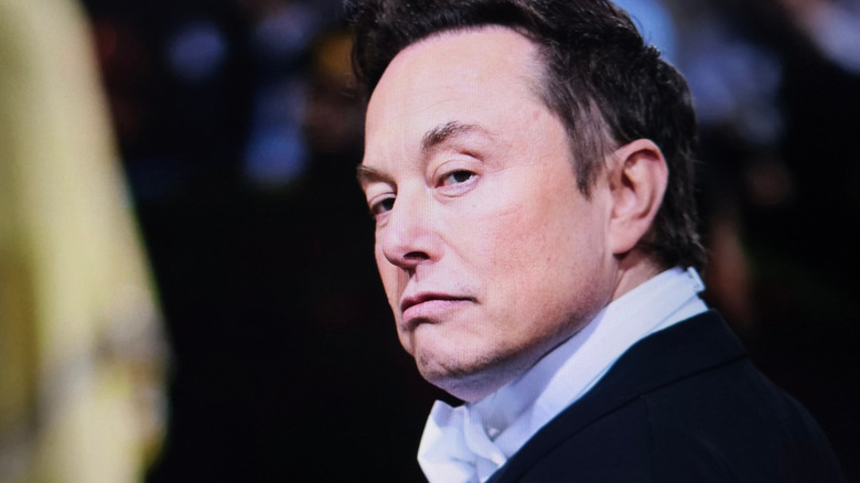 Elon Musk at an event, captured in a medium shot, showing his serious expression