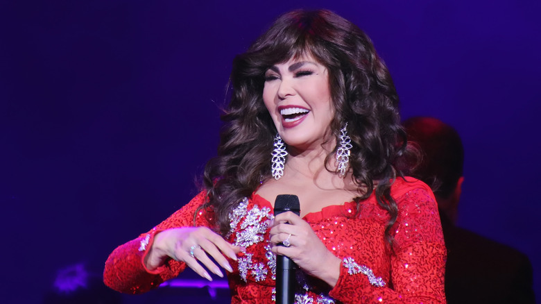 Marie Osmond holding a microphone on stage in December 2021