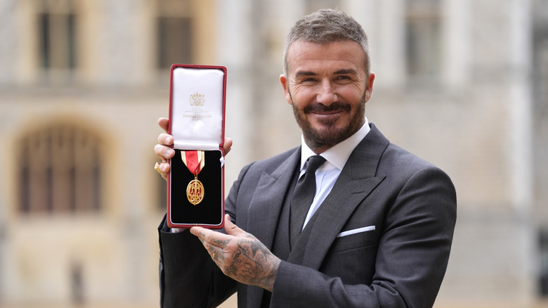 David Beckham holding up his knighthood medal