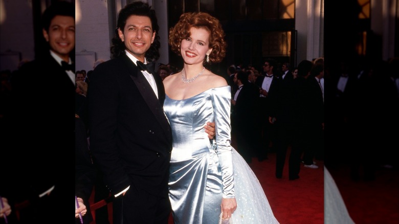 Geena Davis and Jeff Goldblum smiling on the red carpet at the Oscars.