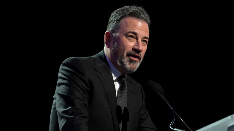 Jimmy Kimmel standing a podium with a black background.