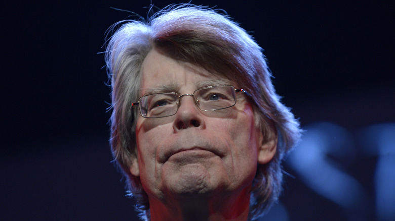 Stephen King under a blue light and low angle looking off to the left.
