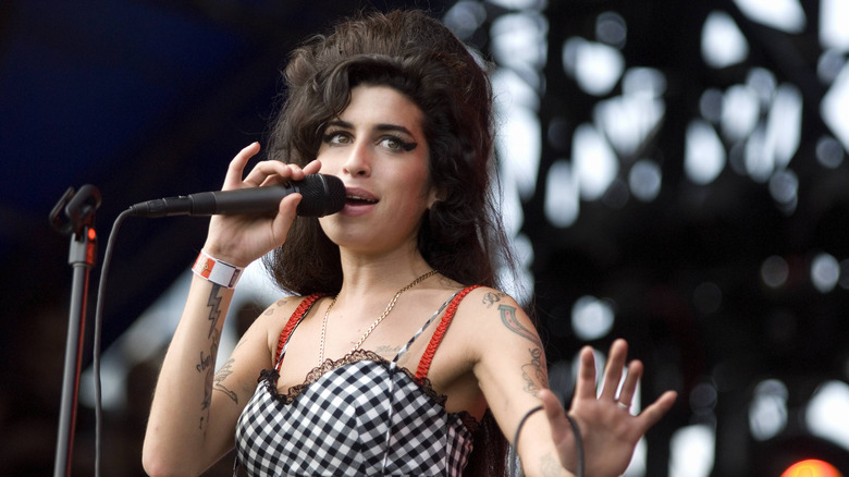 Amy Winehouse singing into a microphone onstage