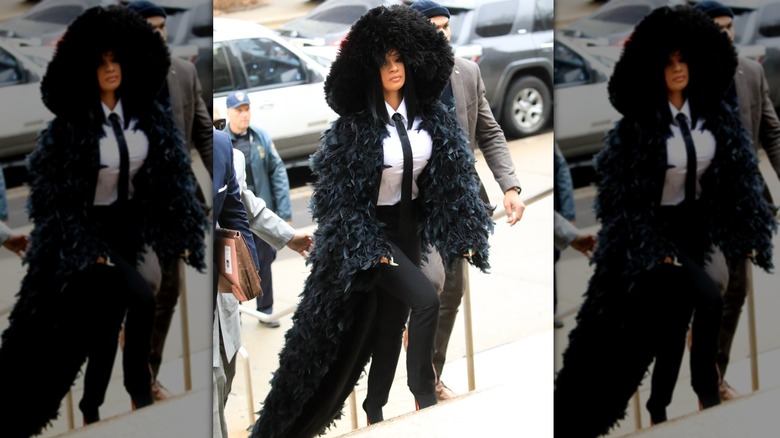 Cardi B walking up courthouse steps in a feather and fur coat