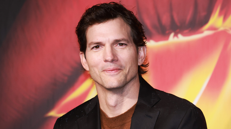 Ashton Kutcher wearing a black blazer over a brown sweater