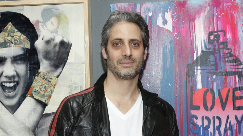 Josh Saviano posing in front of artwork in 2018