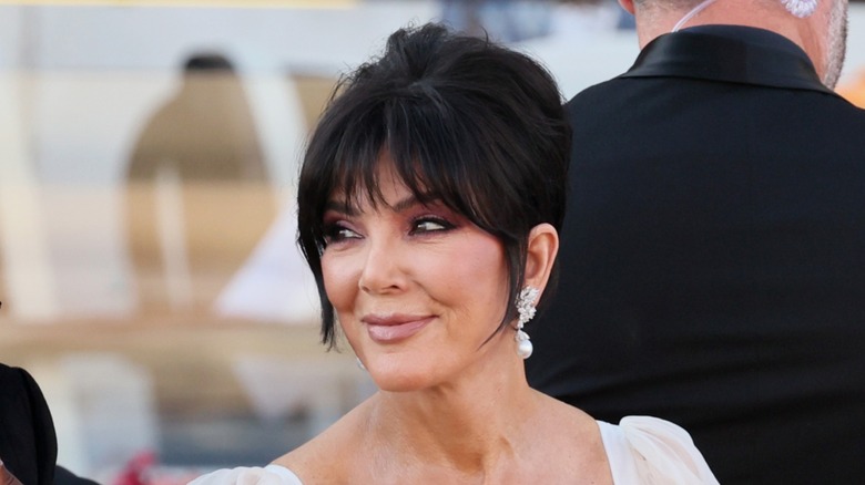 Kris Jenner smiling while wearing dangling earrings