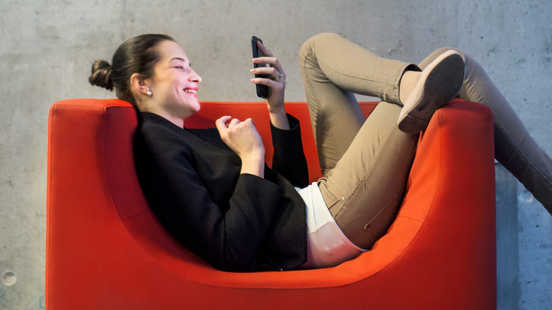 woman laughs as she reads her phone 