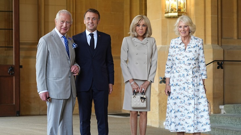 King Charles III, President Emmanuel Macron, Madame Brigitte Macron, and Queen Camilla standing in a line and smiling