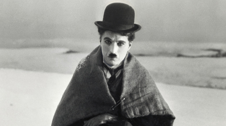 Charlie Chaplin posing with blanket over shoulders held together by safety pin 1925