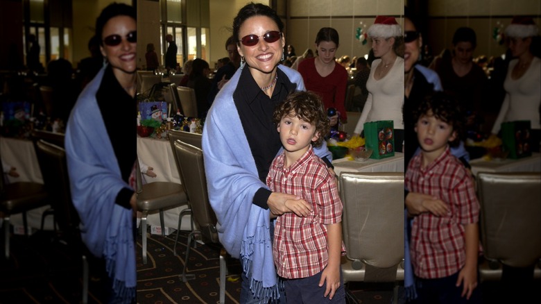 Julia Louis-Dreyfus smiling with a very young Charlie Hall at a Christmas charity event.