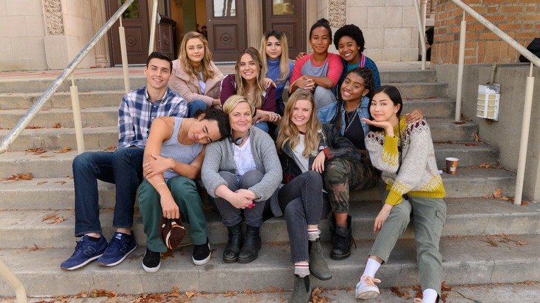 Charlie Hall smiling with the cast of Moxie and its director, Amy Poehler.