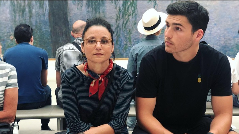 Julia Louis-Dreyfus and Charlie Hall sitting next to each other on a museum bench.
