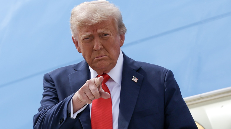 Donald Trump pointing at someone as he exits Air Force One in a suit