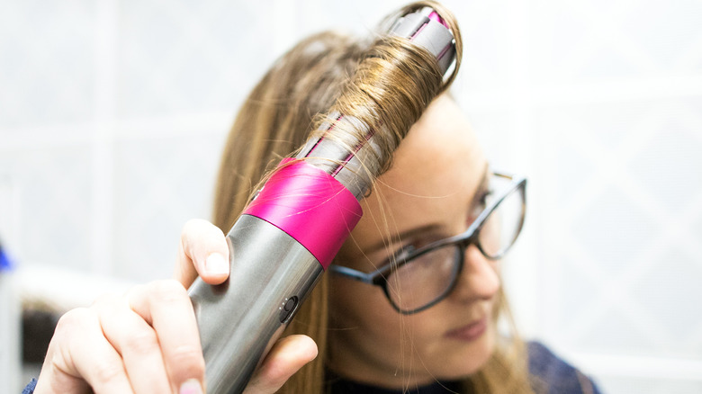 Woman using Dyson Airwrap to curl her hair.