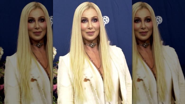 Cher smiles in a white jacket and long blond hair