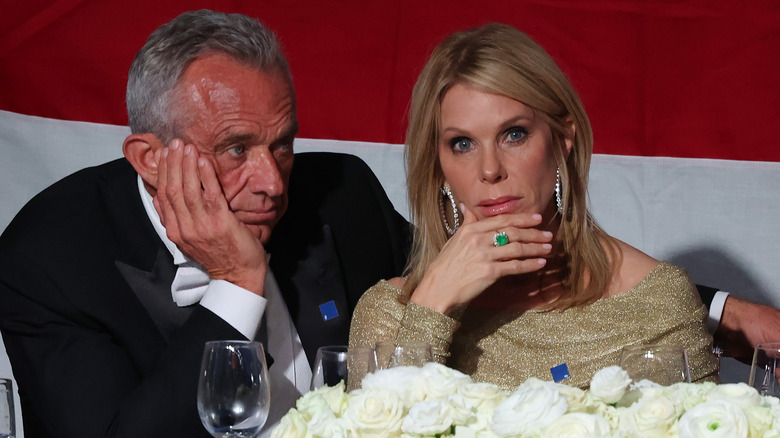 Cheyl Hines and RFK Jr. looking concerned while sitting at a table at a glitzy event