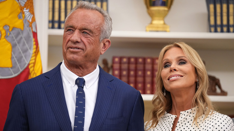 Cheryl Hines and RFK Jr. smiling while listening to someone speak