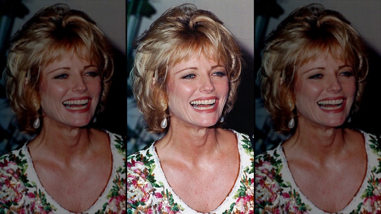 Cheryl Tiegs smiles widely in a choppy layerd bob with microbangs in a sequined floral top and pearl earrings
