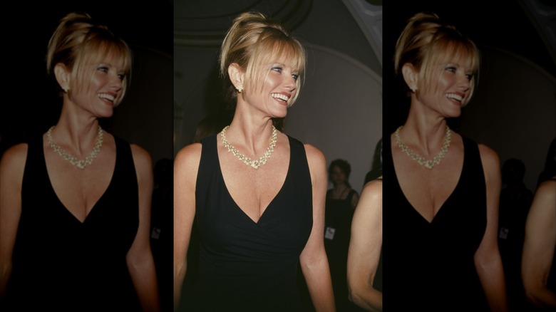 Cheryl Tiegs in a lowcut black dress laughing off to the side with her hair up in an updo with bangs