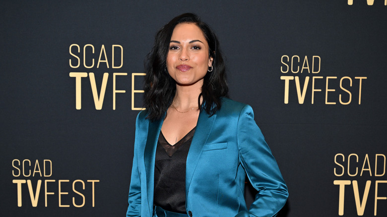 Monica Raymund wearing teal and black in front of a black background