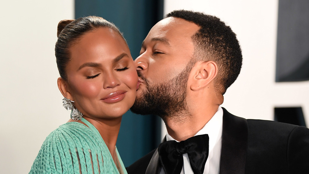 Chrissy Teigen eyes closed getting kiss on the cheek from John Legend